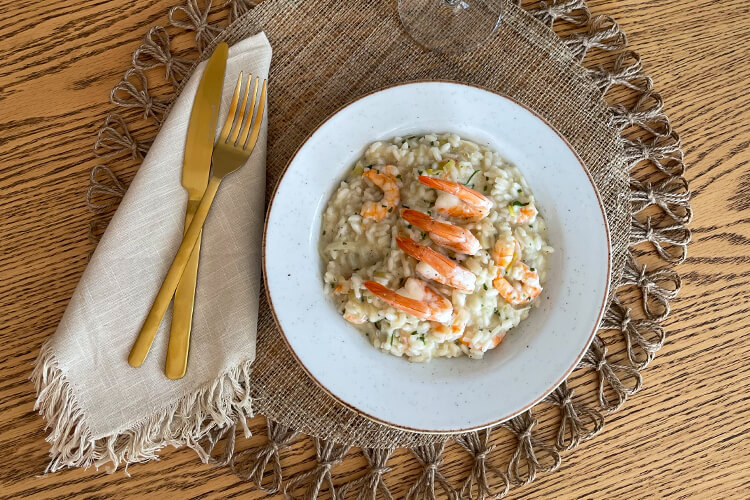 Foto de um prato e talheres com Risoto de Camarão com Alho Poró e Limão Siciliano